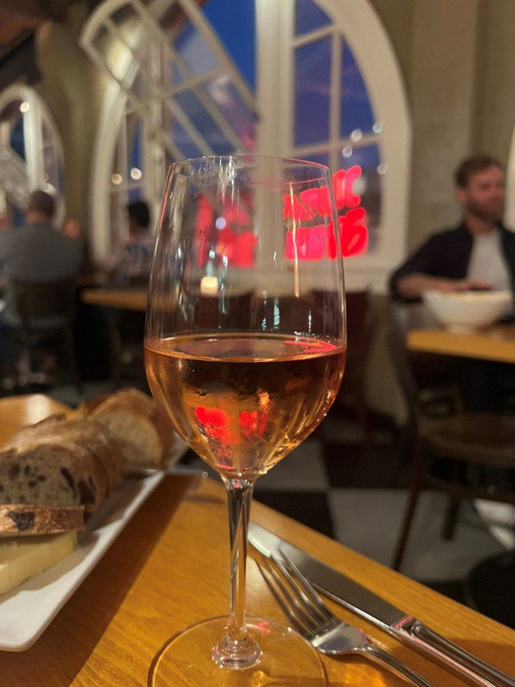 A glass of rosé wine on a table at a cozy restaurant.