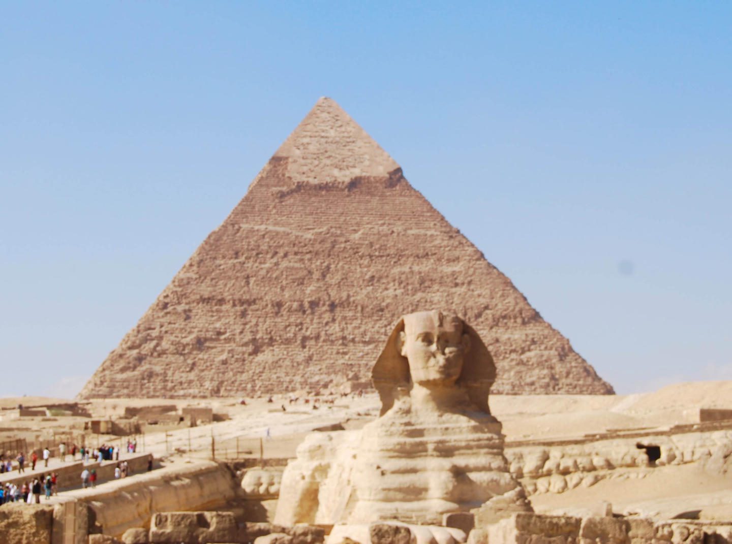 The Great Sphinx with the Pyramid of Khafre in the background under clear blue sky.
