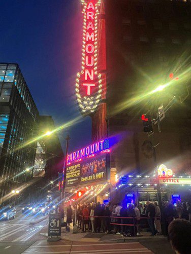 Bright neon lights illuminate the bustling city street at night.