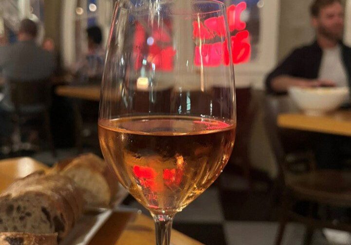 A glass of rosé wine on a table at a cozy restaurant.
