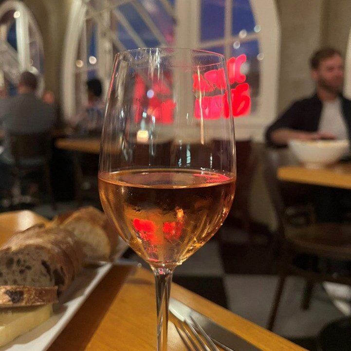 A glass of rosé wine on a table at a cozy restaurant.