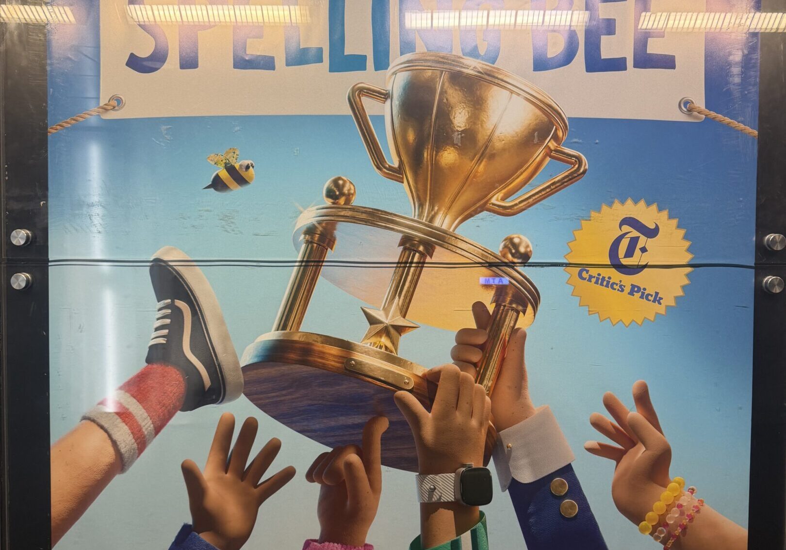 Spelling Bee poster showing trophy and hands
