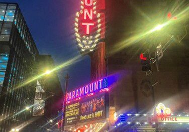 Bright neon lights illuminate the bustling city street at night.