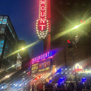 Bright neon lights illuminate the bustling city street at night.