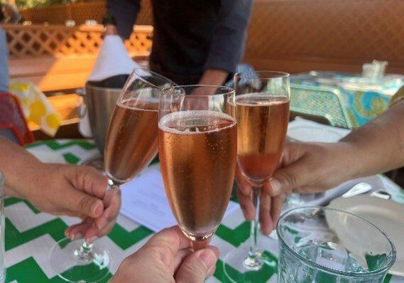 People toasting with glasses of rose wine in an outdoor setting.